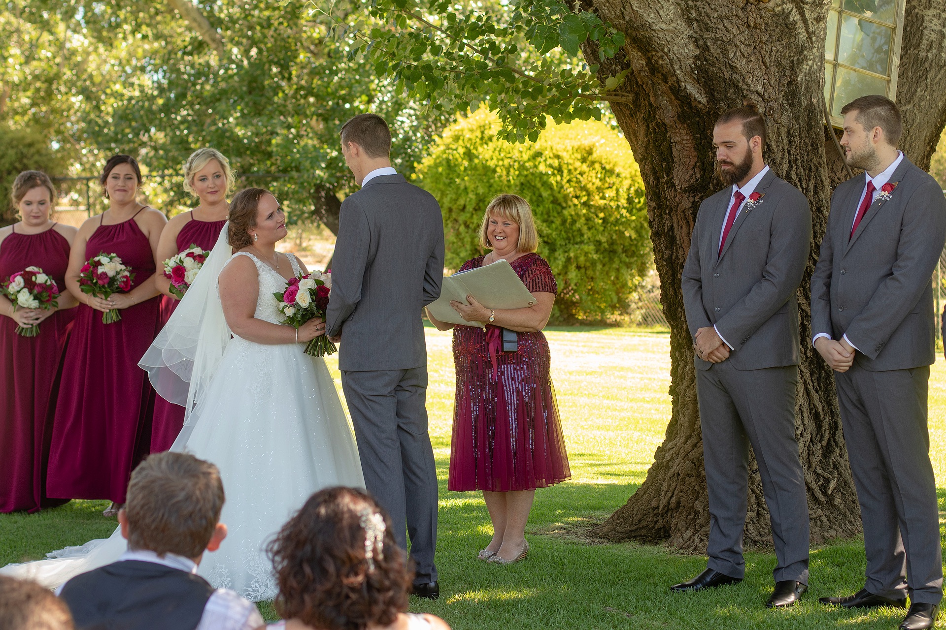 Julie Chesson conducting a wedding ceremony under a large shady tree
