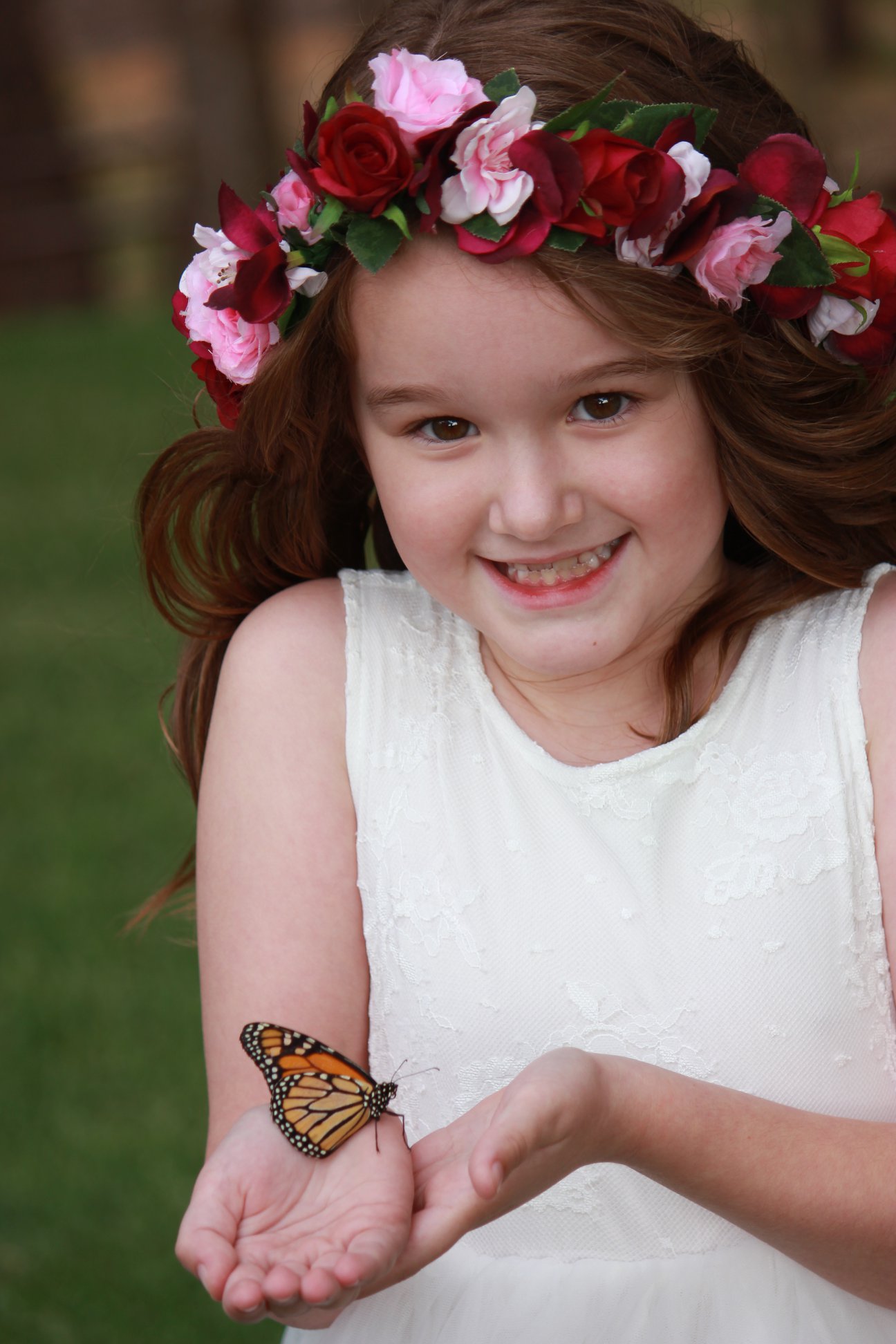 Smiling flower girl holding a monarch butterfly