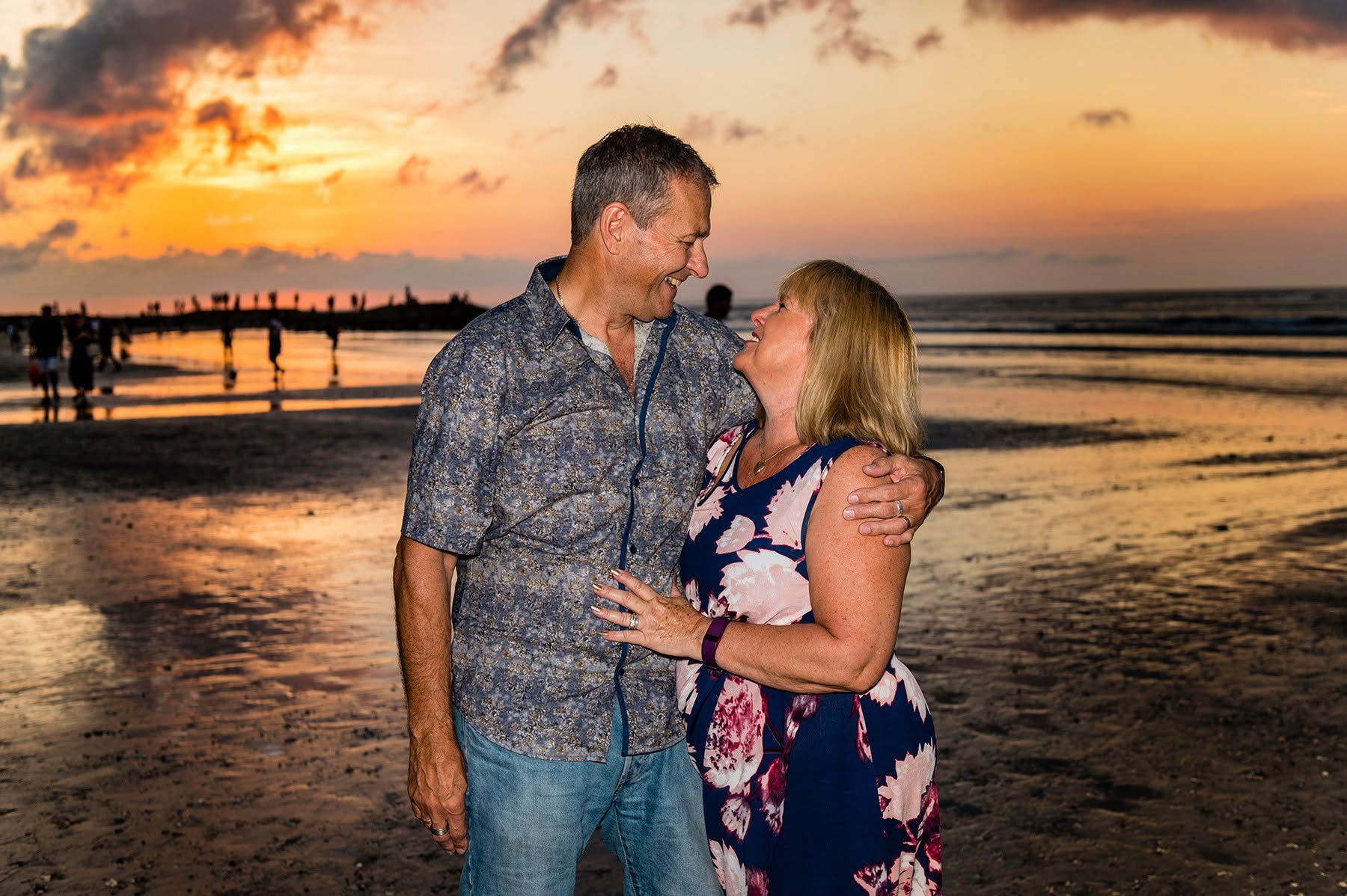 Julie and Keith laughing together on the beach at sunset